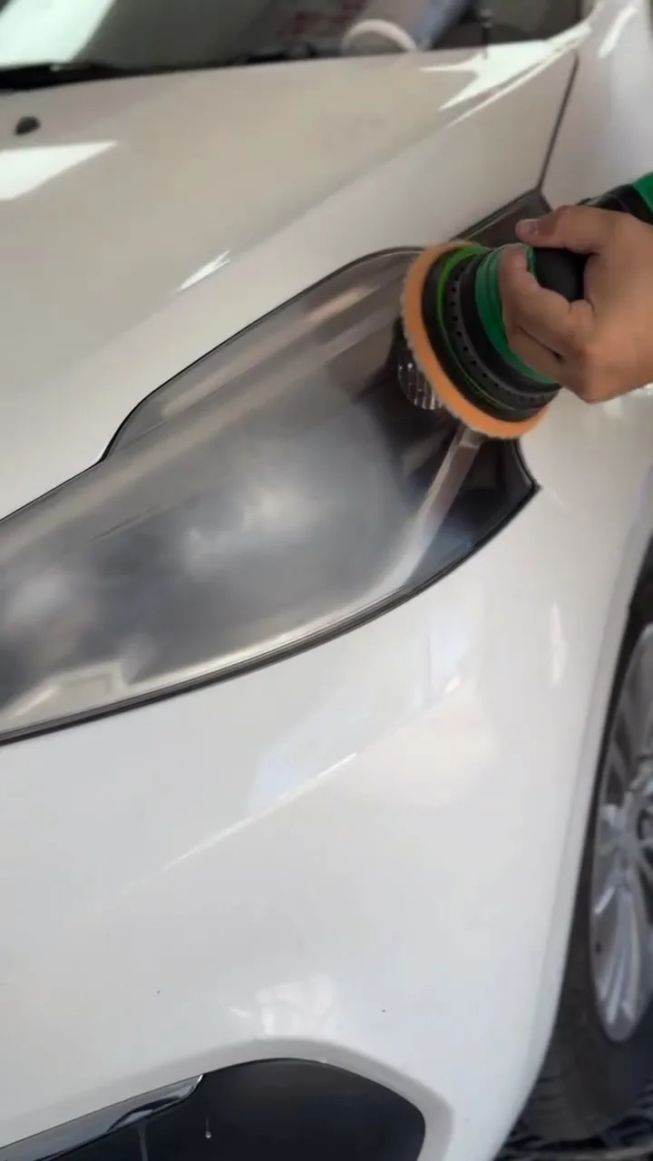 Pulidora trabajando sobre la óptica de un auto blanco